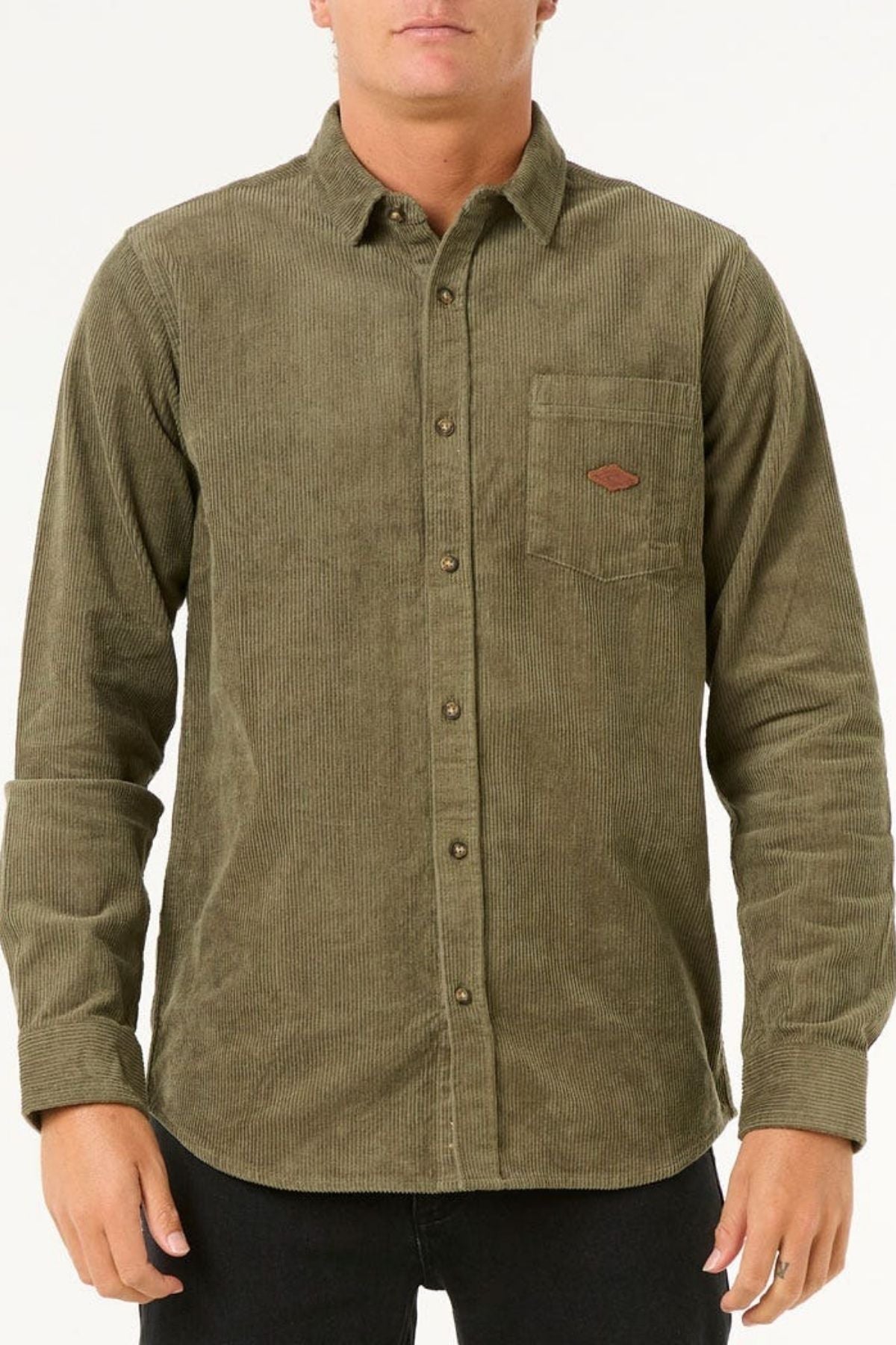 A person is wearing the Rip Curl Classic Surf Cord Shirt, an olive green long-sleeve collared corduroy shirt with a button front and chest pocket, standing against a plain white background.