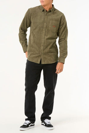 Someone wearing the Rip Curl Classic Surf Cord Shirt in green, black pants, and black-and-white sneakers stands against a plain white background.