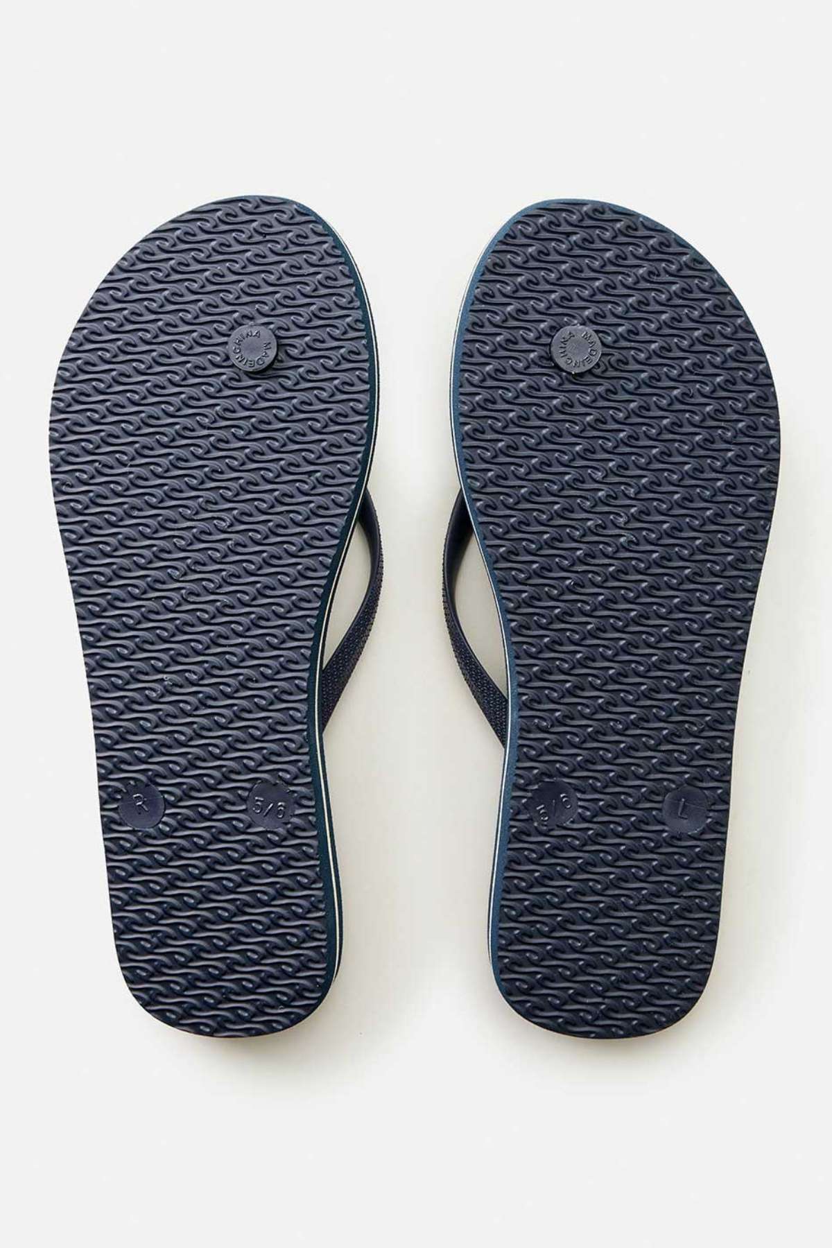 A pair of Rip Curl Classic Surf Bloom Thongs in dark blue, featuring BLOOM algae-blended foam and ergonomic molded straps, is shown from the bottom and displayed side by side on a light gray background.