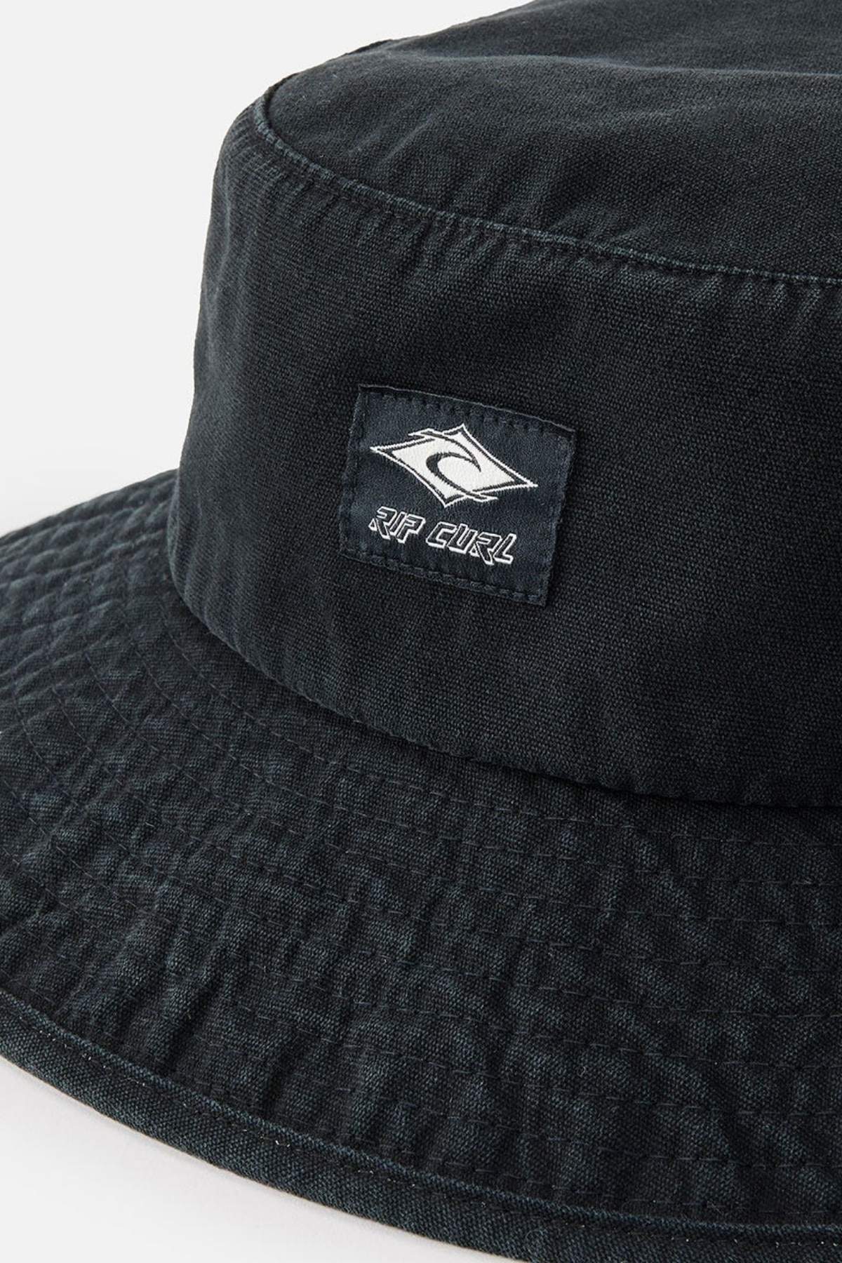 Close-up of the Rip Curl Classic Surf Mid Brim Hat in black cotton, featuring the iconic Rip Curl logo with its signature wave design and text. Ideal for outdoor adventures, this hat displays a subtle textured pattern concentrated on the upper section.