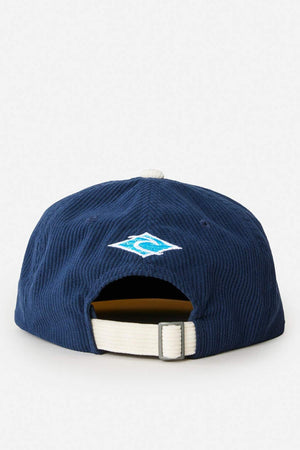 The Rip Curl Diamond Adj Cap in navy blue features 11 wale cord, a white adjustable strap with buckle at the back, and a small blue and white embroidered logo above the rear opening.