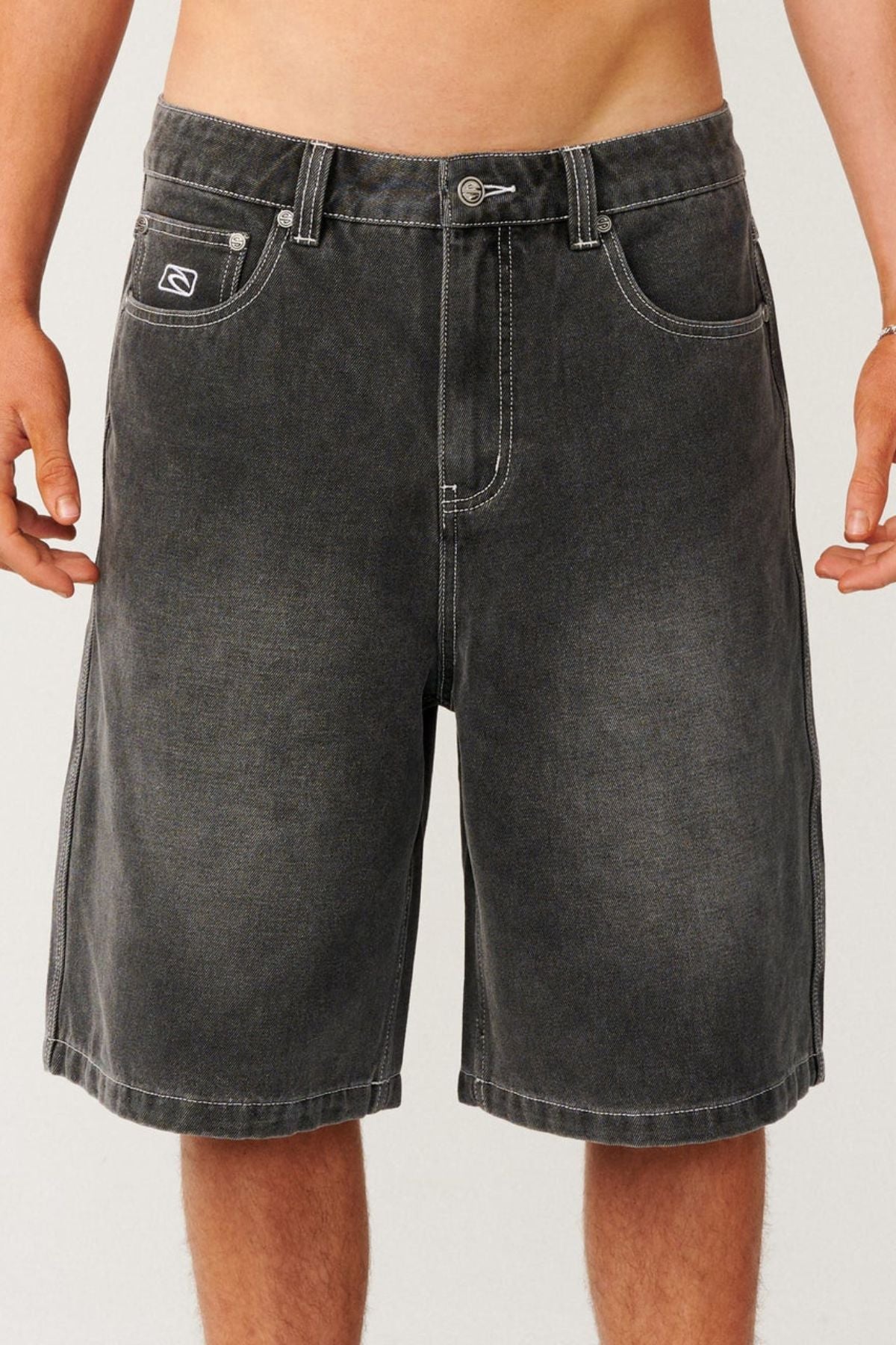Rip Curl Archive Dirty Denim Walkie Walkshort, featuring relaxed baggy black denim with white contrast stitching and a small logo patch on the front pocket.
