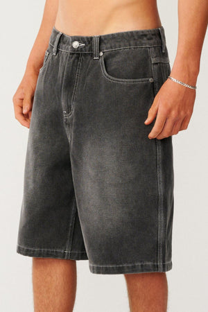 A person wearing relaxed, baggy charcoal grey Rip Curl Archive Dirty Denim Walkie Walkshort with white contrast stitching.