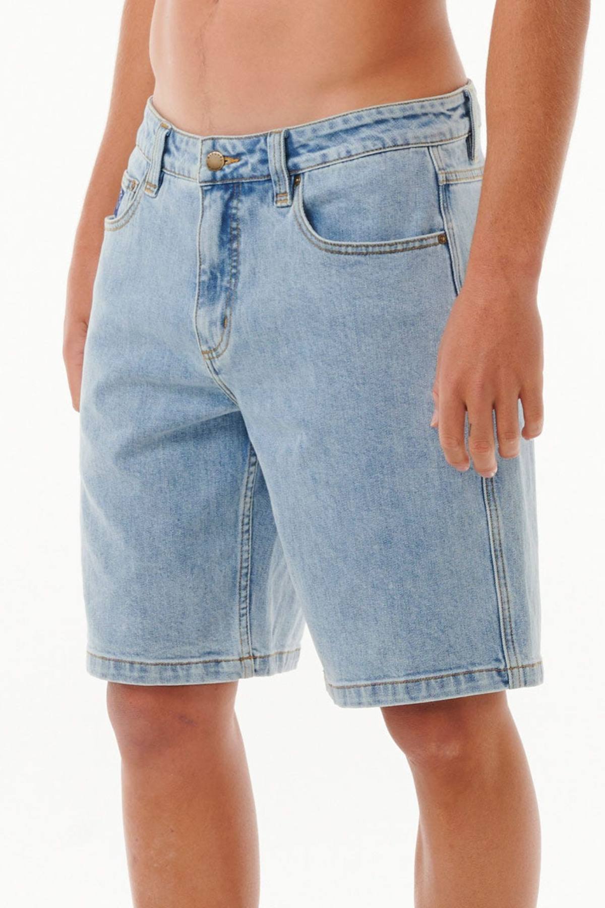 A person wearing Rip Curl Dosed Denim Walkshorts in light blue stands against a plain white background. The shorts have pockets and a button closure. Only the lower torso and upper legs are visible.
