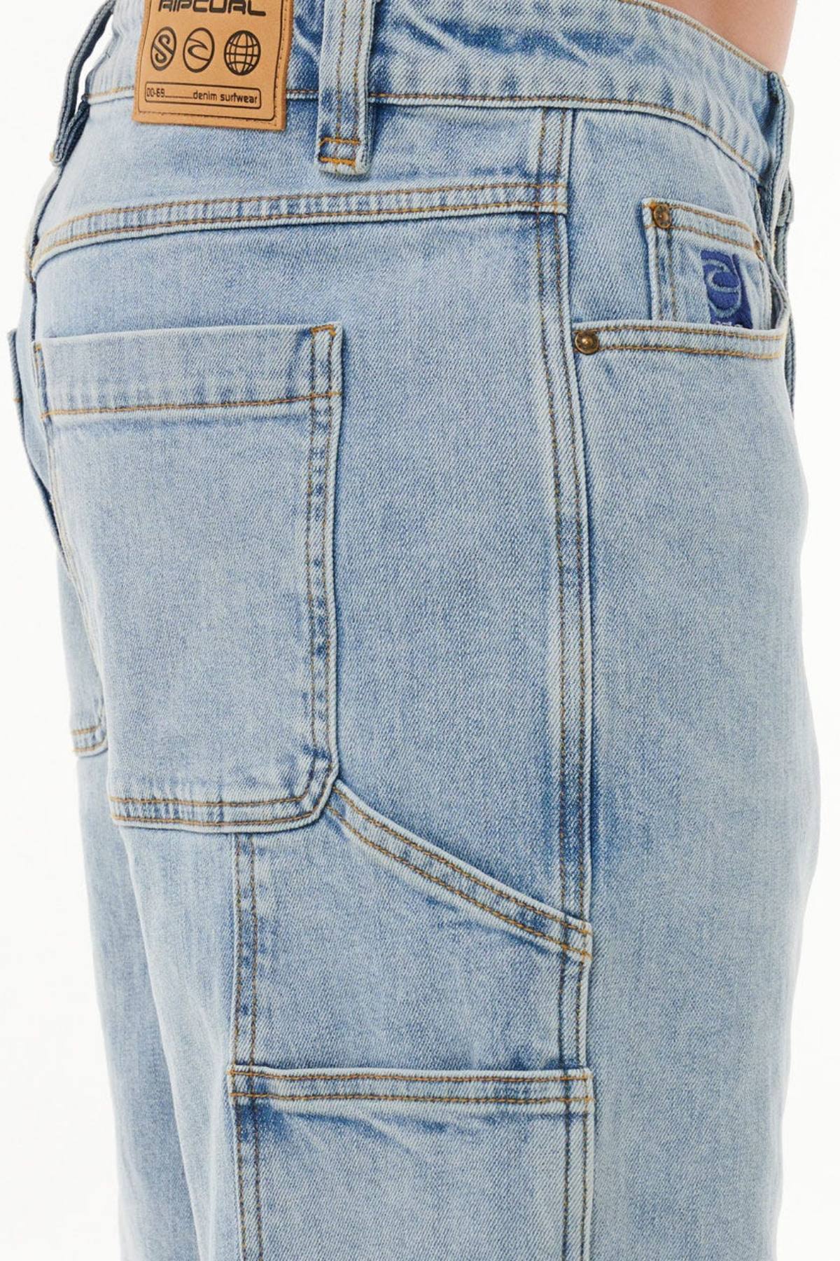 Close-up of the Rip Curl Dosed Denim Walkshort in light blue cotton denim, featuring multiple pockets, bold stitching, and a brown leather logo patch on the waistband. Shown worn on the hip and upper thigh for a relaxed fit.