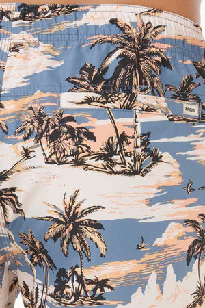 Close-up of Rip Curl Dreamers Volley shorts with a tropical beach print in pastel blue, pink, and beige. Quick-dry fabric and a small “Rip Curl” logo tag above the back pocket.