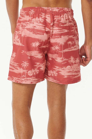 A person stands with their back to the camera wearing the Rip Curl Dreamers Volley board shorts, boasting a stylish white palm tree print on red recycled fabric and an elastic waistband. The background is off-white.