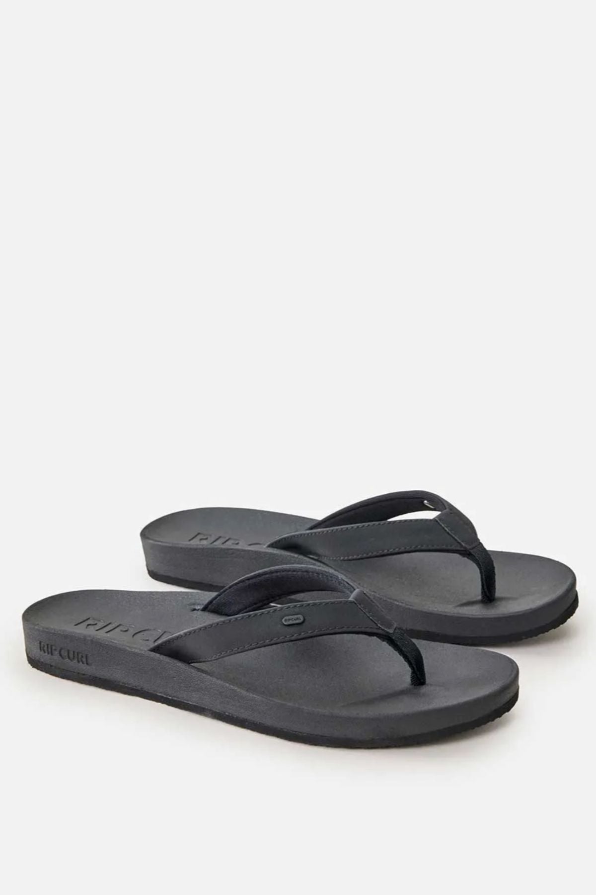 A pair of Rip Curl Essential Contour Bloom Thongs in black with thin straps and a flat sole, displayed on a plain white background. The Rip Curl brand name is embossed on the side for a sleek finish.