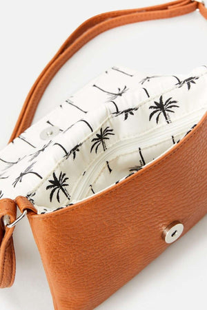 The Rip Curl Essentials II Festival Bag is a brown textured handbag with an open interior, showcasing a white lining adorned with black palm tree designs. It features a flap that closes with a magnetic snap and includes an adjustable shoulder strap for versatile styling, capturing the essence of Rip Curl's adventure-ready design.