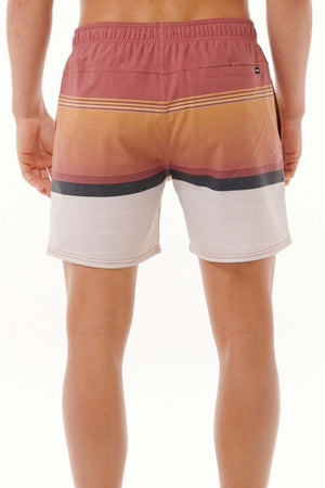 A rear view of someone sporting the Rip Curl Fun Times Volley swim trunks, showcasing a striped design. These water-repellent shorts display a mix of pink, orange, black, and white colors on a simple white backdrop.