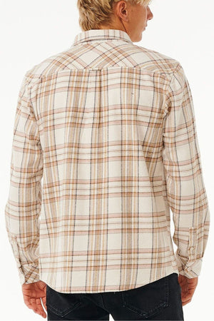 A person with short blond hair is seen from the back, wearing a cream plaid Rip Curl Griffin Flannel Shirt with brown and tan lines made from quality cotton flannel, paired with black pants.