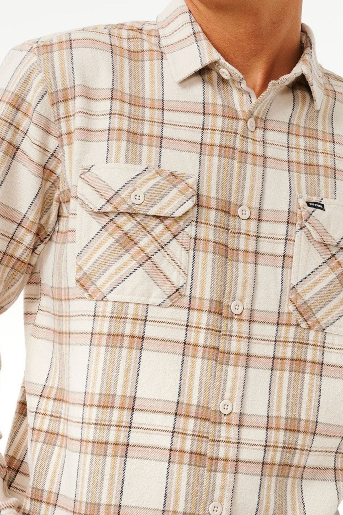 A close-up shows only the upper torso of a person in the Rip Curl Griffin Flannel Shirt, a beige plaid cotton flannel with two chest pockets with button flaps and a collar.