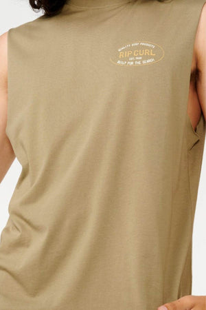 A person wearing the Rip Curl Hallmark Muscle, a sleeveless shirt in light brown made from 100% cotton, showcases a small chest logo displaying "RIP CURL" and "BUILT FOR THE SEASON.