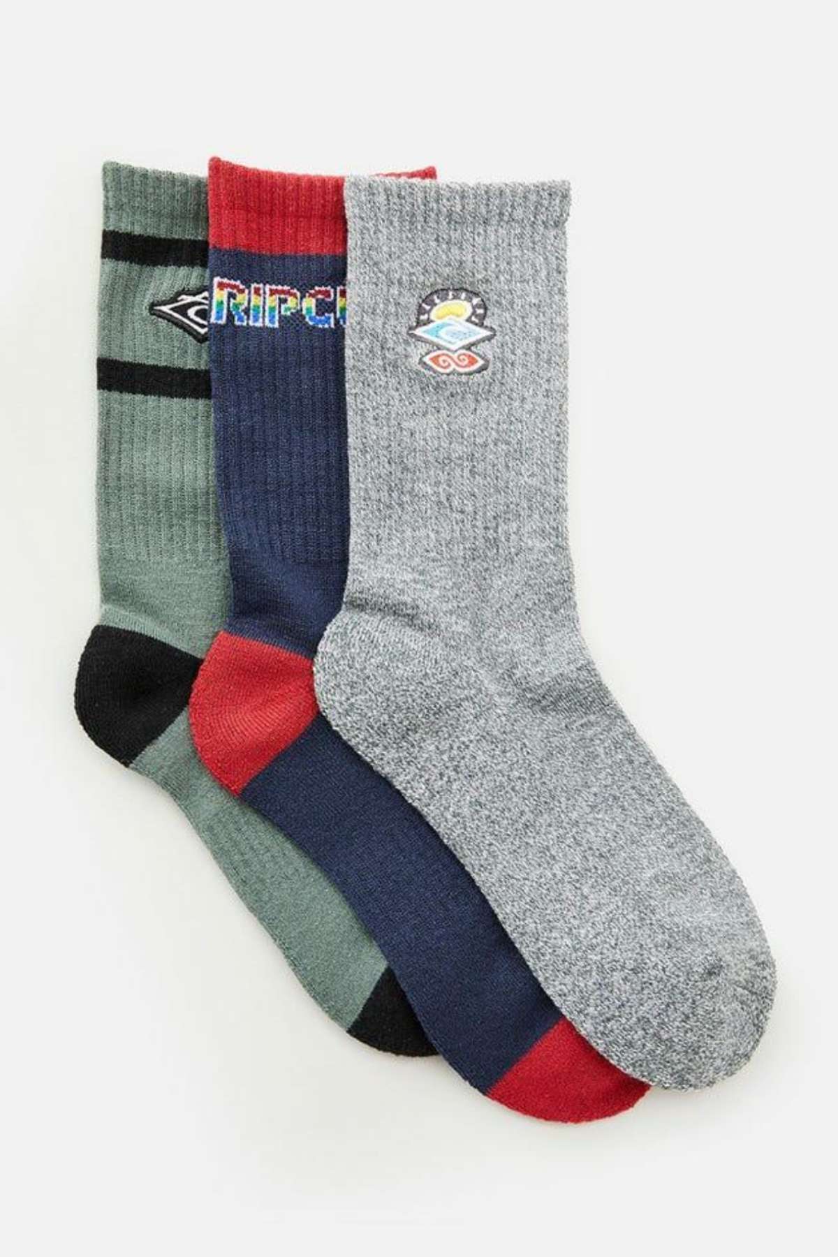 The Rip Curl Icons Crew Sock 3 Pack is showcased with three overlapping pairs, each boasting vibrant designs: one in green with black and gray accents, another in blue featuring red and multicolored text, and the last pair in gray highlighting a mountain and sun emblem. Each sock is designed with arch support to enhance comfort, illustrating Rip Curl's dedication to quality.