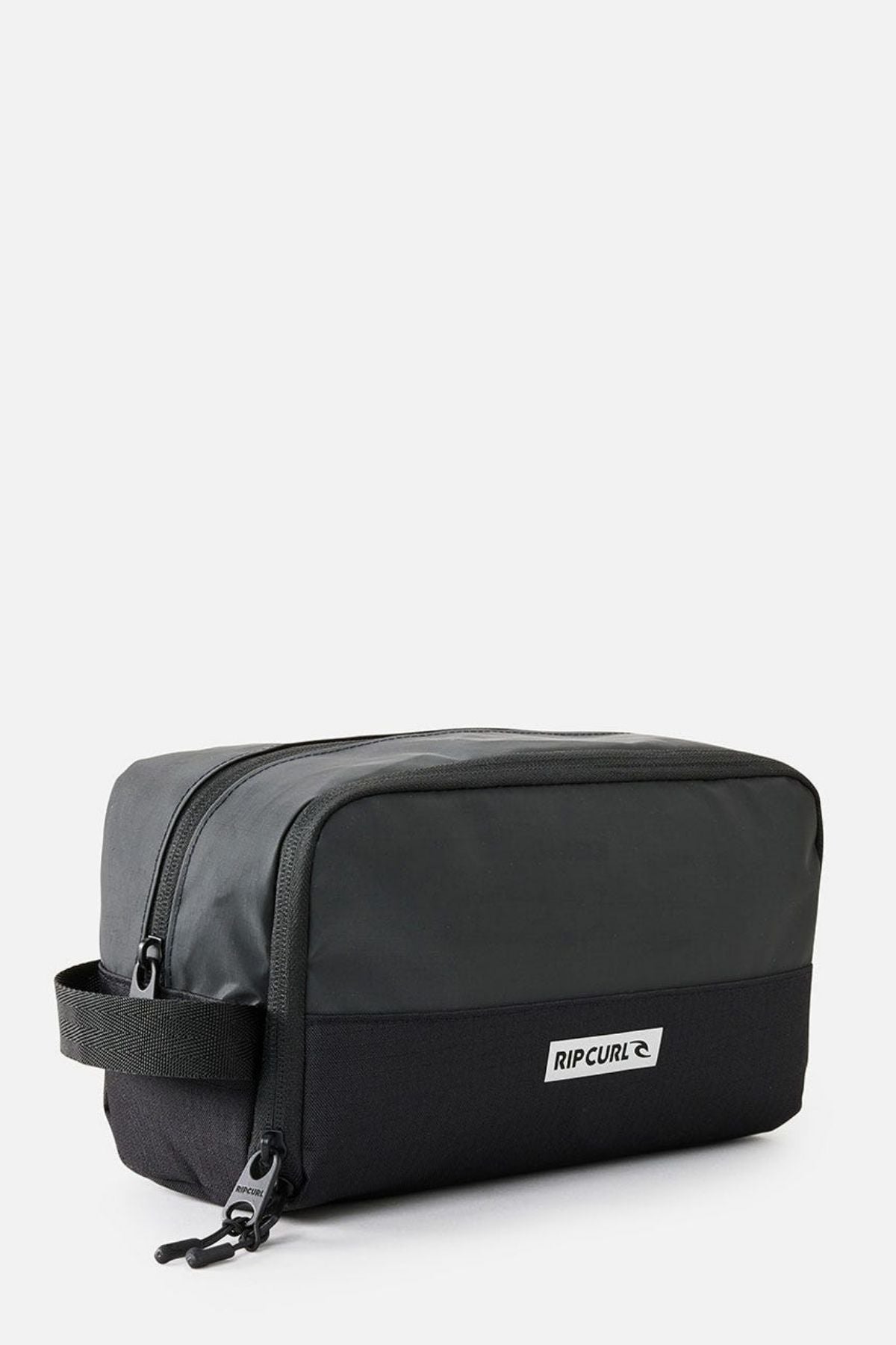The Rip Curl Icons Groom Toiletry Bag is a black and dark gray rectangular toiletry bag with a zipper and a small handle on one side, making it perfect for travel. Featuring the "Rip Curl" logo on the front, this stylish bag ensures your essentials stay organized against a plain white background.