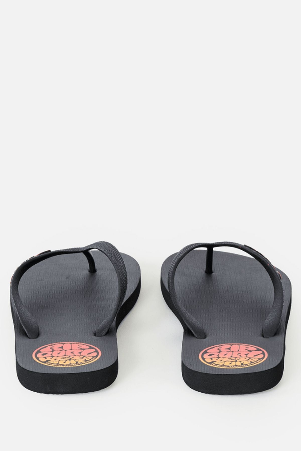 A pair of Rip Curl Icons Of Surf Bloom Open Toe Sandals with thin black straps and a round orange and yellow logo on the heel area, crafted from eco-friendly BLOOM algae foam, displayed on a plain white background.