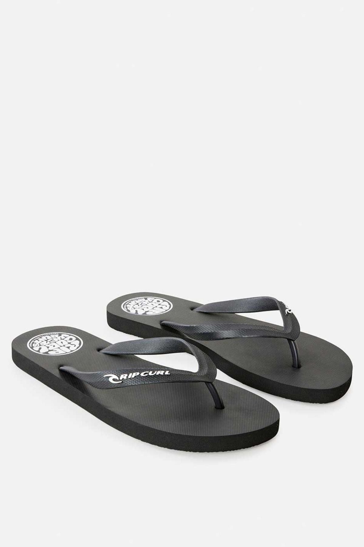 A pair of Rip Curl Icons of Surf Bloom Thongs in classic black showcases white circular designs on the heel area. The ergonomic molded strap is styled for comfort, with the brand name "Rip Curl" elegantly printed in white on both the straps and footbeds. Crafted from eco-friendly materials, these thongs are presented against a plain white background.