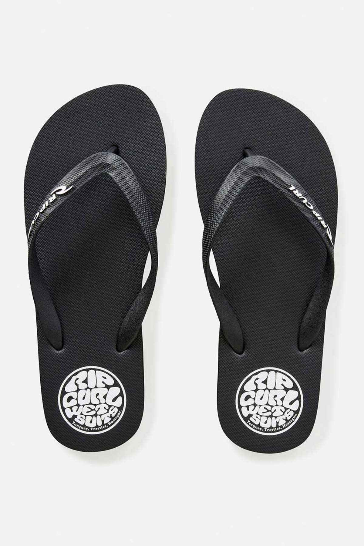 A pair of Rip Curl Icons of Surf Bloom Thongs in black, featuring ergonomic molded straps. The footbeds are adorned with a circular white logo that reads "RIP CURL WETSUITS" on each sandal, elegantly placed side by side on a crisp white background.