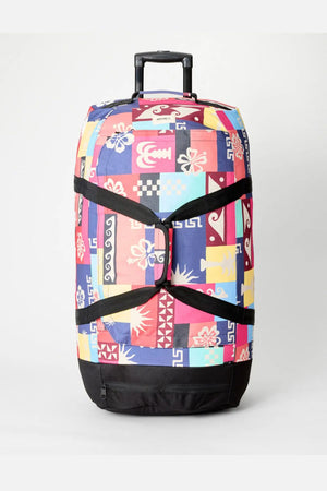 The Rip Curl Jupiter 80L Mixed Travel Bag features a vibrant patchwork of abstract shapes, black straps and base, and is crafted from recycled polyester—perfect luggage for stylish journeys.