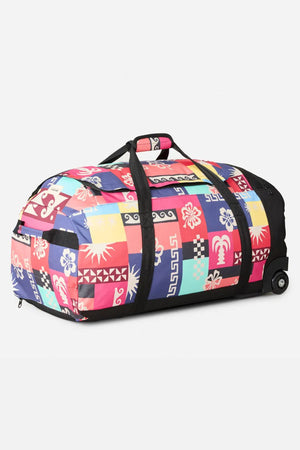 The Rip Curl Jupiter 80L Mixed Travel Bag features a colorful patchwork of flowers, geometric shapes, and tropical motifs on recycled polyester, shown against a light background.