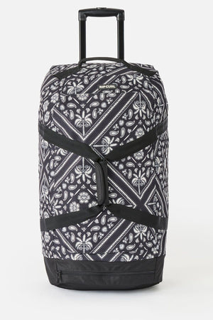The Rip Curl Jupiter 80L Mixed Travel Bag is a large black and white travel bag with a paisley pattern, telescopic and side handles, 80L capacity, made from recycled polyester. "RIP CURL" branding appears at the top.
