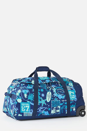 The Rip Curl Jupiter 80L Mixed Travel Bag is a roomy blue and turquoise wheeled bag with handles, featuring tropical patterns like palm trees, waves, and surf graphics—ideal for your next trip.