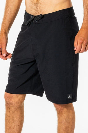 A man wearing black Rip Curl Mirage Core Boardshorts with a drawstring waist, standing against a plain white background.