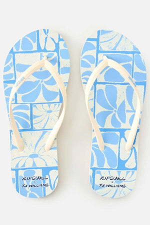 The Rip Curl Mixed Bloom Thongs feature blue footbeds with white straps, a comfy 3-point design, a white floral geometric pattern, and “RIP CURL” plus “TJ WILLIAMS” printed on algae-blended foam EVA footbeds.