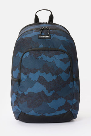 Rip Curl Ozone 30L Camo Check backpack with a blue and black topographical-style print, featuring a front zippered pocket, side mesh pockets, and a top carry handle.
