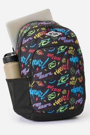 Black 30L Rip Curl Ozone Boy 30L Backpack with a neon-colored graffiti print, a laptop tucked inside, and a water bottle in the side pocket.