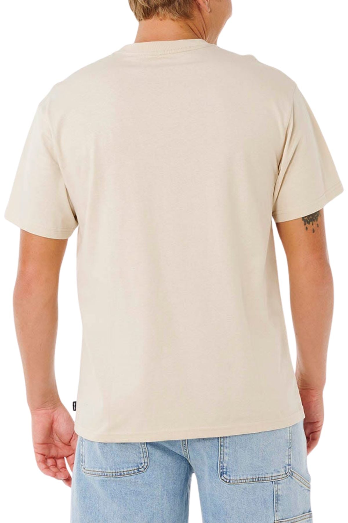 A person with short, light hair is wearing the Rip Curl Pill Icon Tee and light blue denim shorts, standing with their back to the camera. A small tattoo can be seen on their left arm.