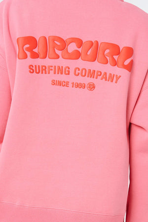 The Rip Curl Surf Puff 1/4 Zip is a pink pullover with “RIP CURL SURFING COMPANY SINCE 1969” in bold, textured red letters on the back, bringing classic surf style to your outfit.