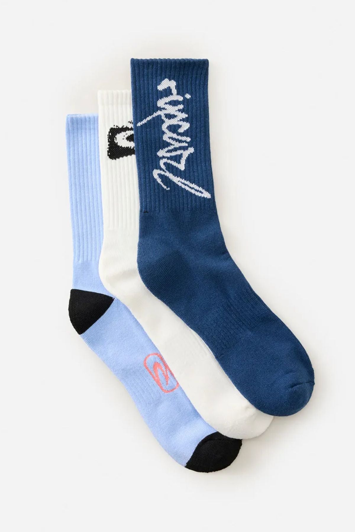 The Rip Curl Retro Crew Sock 3 Pack features three crew socks: blue with white cursive text, white with a black ankle design, and light blue with black toes and a small pink logo—combining comfort and style.