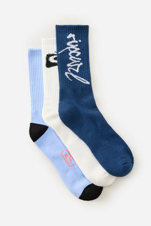 The Rip Curl Retro Crew Sock 3 Pack features three crew socks: blue with white cursive text, white with a black ankle design, and light blue with black toes and a small pink logo—combining comfort and style.