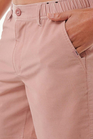 Close-up of a person wearing the Rip Curl Saltwater Culture Cord Boardwalk Short in pink, with one hand in the pocket. The fabric looks soft and subtly textured, equipped with quick-dry technology for added comfort. A button and zipper closure are evident, and the shorts boast a casual, relaxed fit, ideal for any laid-back day.