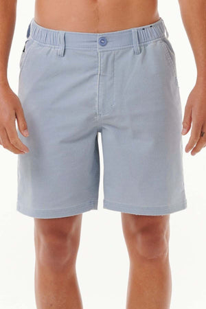 A person wearing Rip Curl Saltwater Culture Cord Boardwalk Shorts in light blue, featuring a button and elastic waistband, stands with their hands by their sides against a plain white background, prepared for a beach adventure. The quick dry technology guarantees comfort all day long.