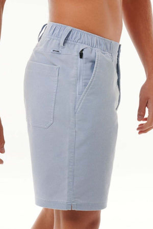 The person is modeling the Rip Curl Saltwater Culture Cord Boardwalk Short in light blue, showcasing its quick-dry technology from a side angle. It includes an elastic waistband, side pockets, and a back pocket, making these shorts ideal for any beach adventure. The individual's torso is bare against a plain white background.