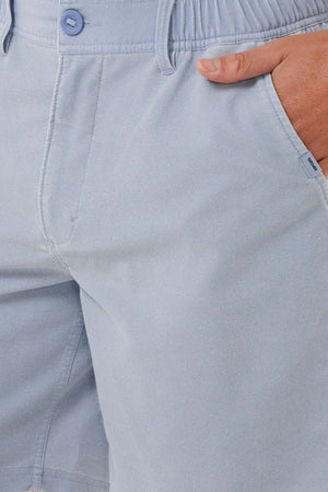 Close-up of a person wearing Rip Curl Saltwater Culture Cord Boardwalk Shorts in light blue, with a hand in the right pocket. These shorts feature an elastic waistband and button fly, making them perfect for a casual beach adventure with their quick-dry technology.