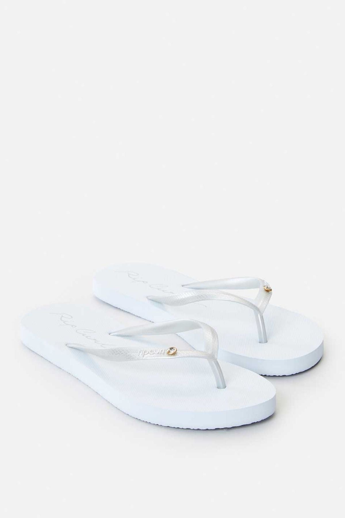The Rip Curl Script Wave Bloom Thongs, with Zori construction, present white flip-flops adorned with transparent straps and circular metallic details on a clean white background.
