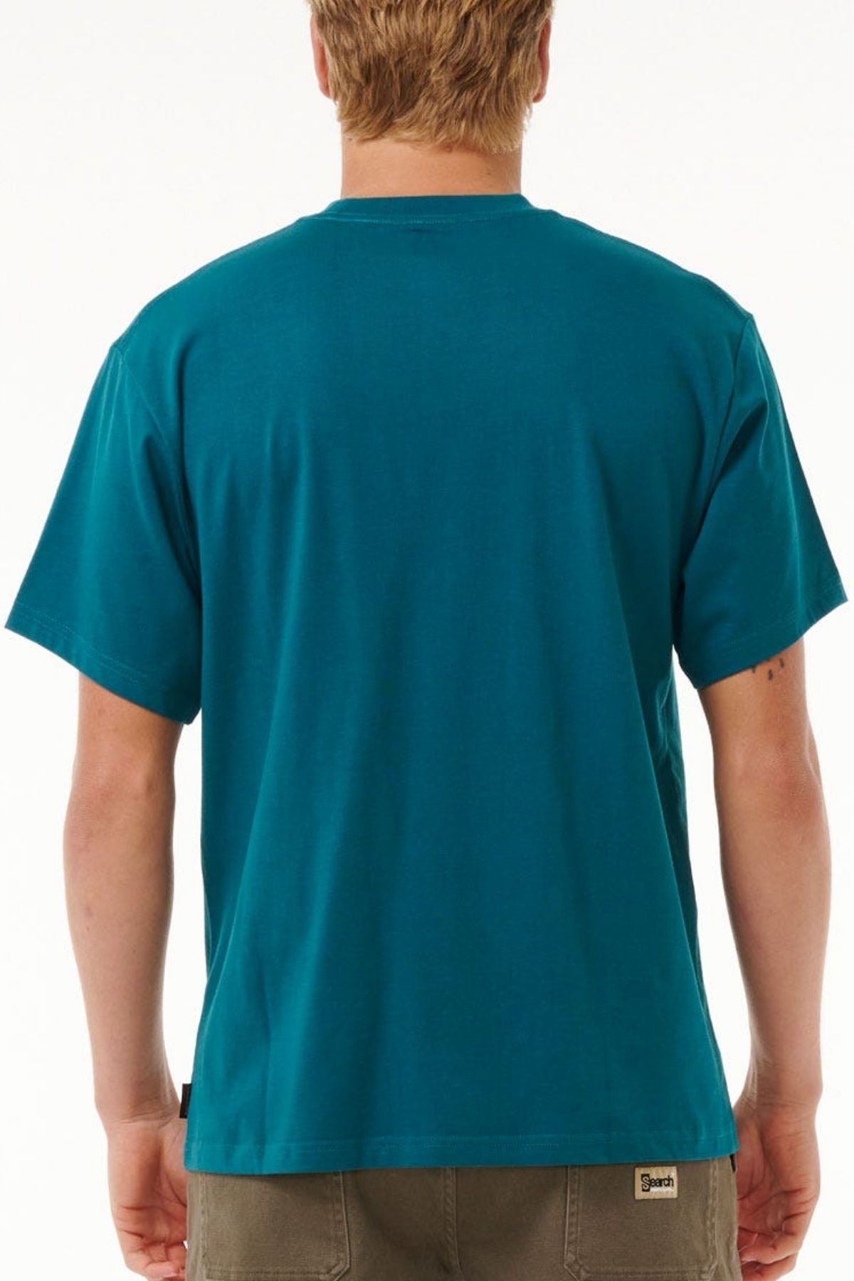 Rear view of a person in a Rip Curl Search Embroidery Tee, reminiscent of the brand's casual style, and olive green pants with a small beige patch above the back pocket. Background is plain white.