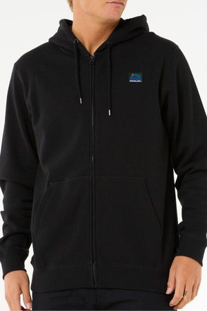 A person wearing a black Rip Curl Search Zip Thru Hood with a small, colorful mountain patch on the left chest stands against a white background. This standard fit hoodie is crafted from a soft cotton-polyester blend for comfort all day.
