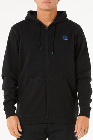 A person wears a Rip Curl Search Zip Thru Hood—plain black, cotton polyester blend, standard fit, with a small colorful rectangular patch on the left chest—standing against a white background.