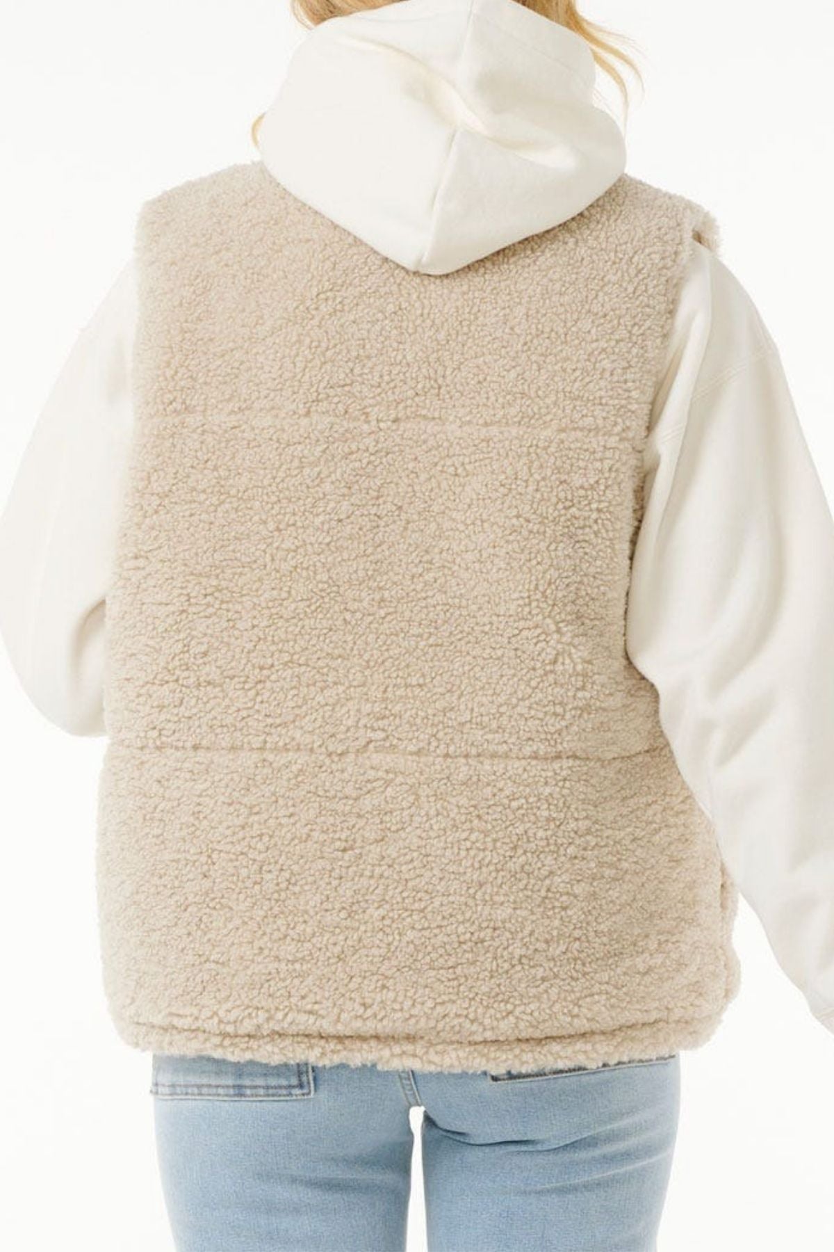 A person wearing the Rip Curl Soleil Revo Puffer Vest in cream over a white hoodie and light blue jeans, shown from the back against a white background.