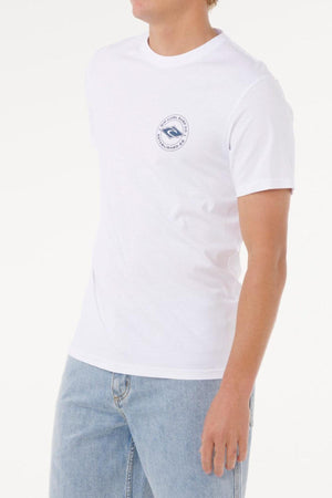 Wearing the Rip Curl Staple Tee, a men's soft cotton jersey shirt with a small circular blue logo on the left chest, and light blue jeans, a person stands against a white background.