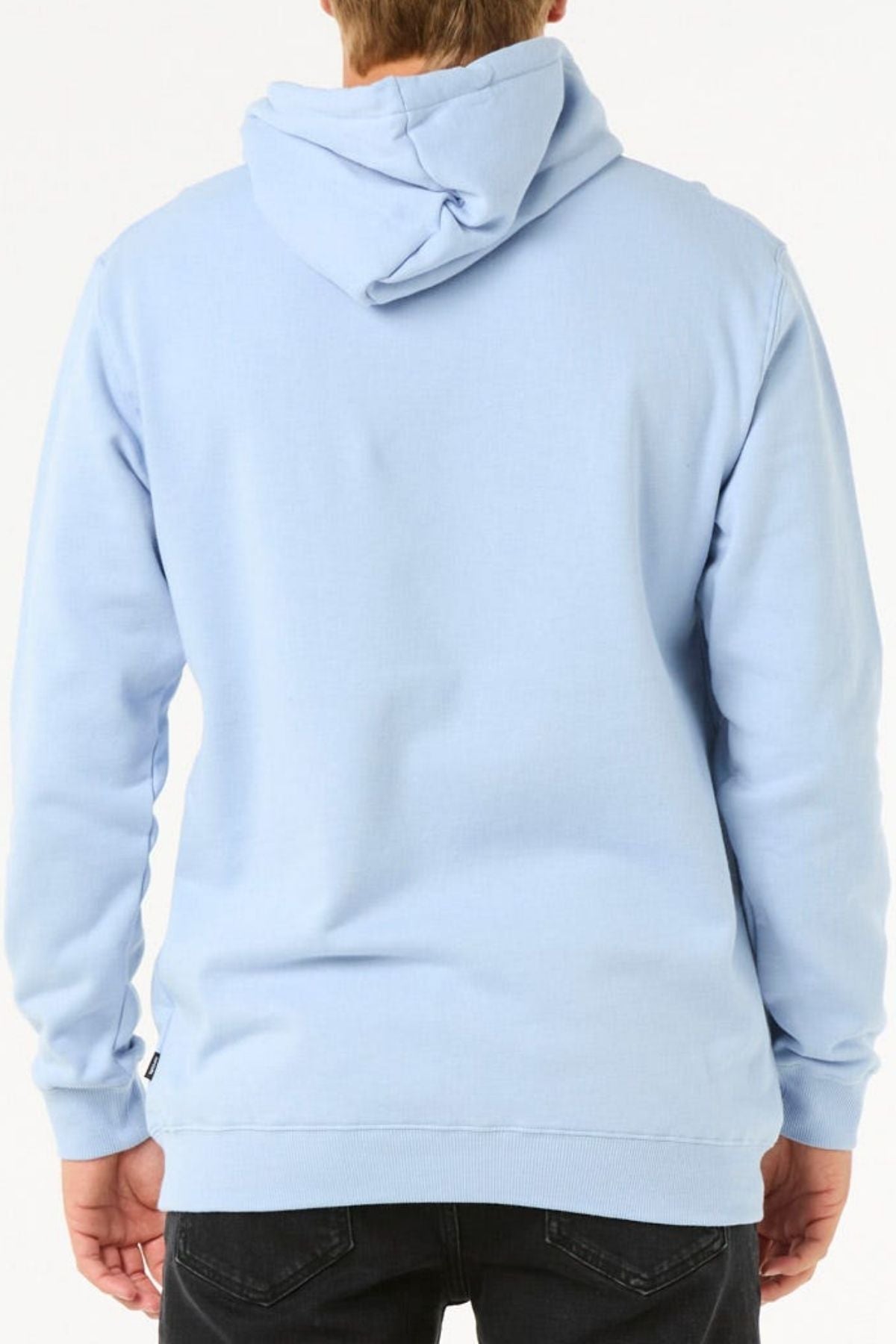 Facing away from the camera, a person wears a light blue Rip Curl Stapler Hood fleece hoodie and black jeans. The hood is up but not on their head, with a plain white background.