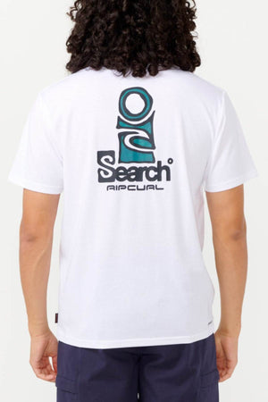 A person wearing a white Rip Curl Vaporcool Search Stack Tee, which displays a large "Search" logo on the back with abstract design elements in teal and black. The shirt is designed with quick-drying fabric for all-day comfort. They have long, curly hair and are also wearing dark shorts.