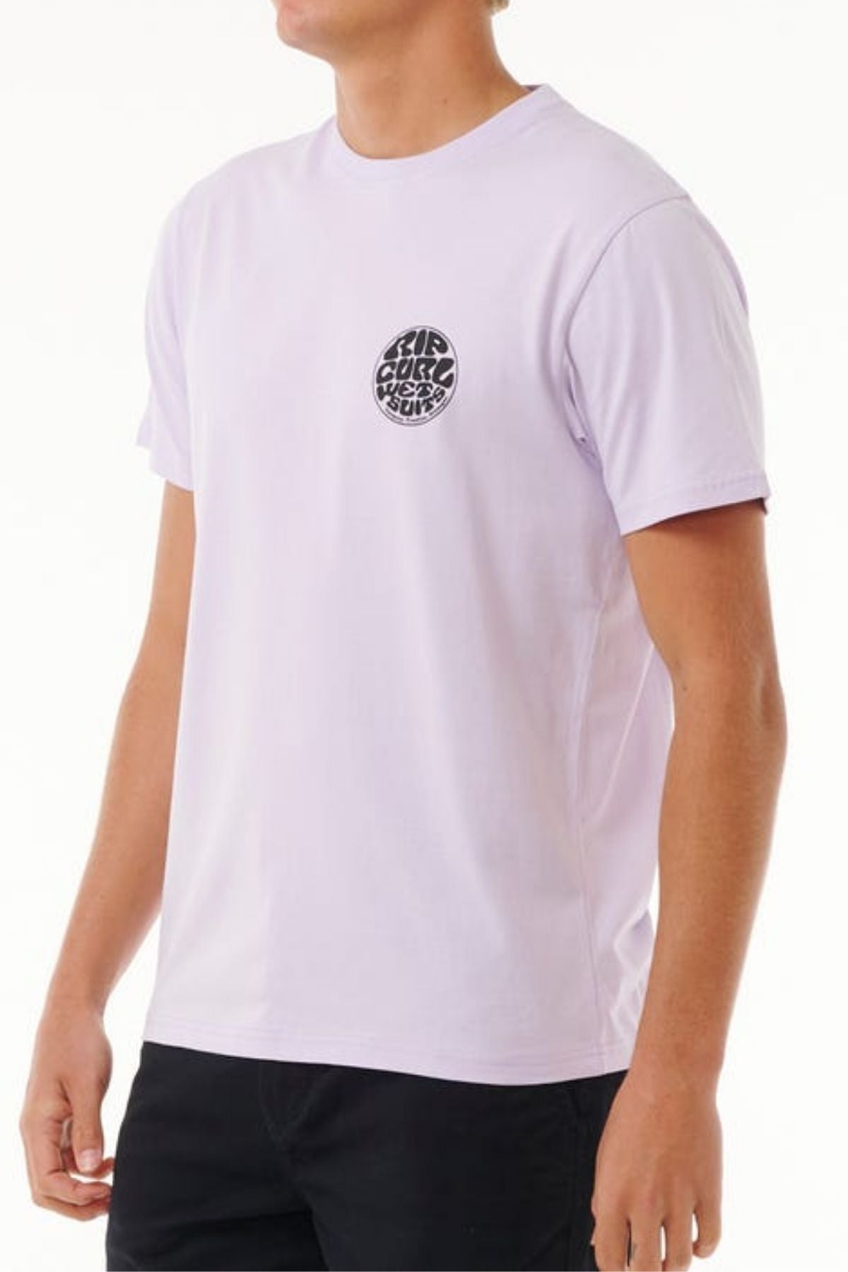 A person in a lightweight cotton, plain white Rip Curl Wetsuit Icon Tee with a small circular black logo on the chest and black pants stands against a light background.