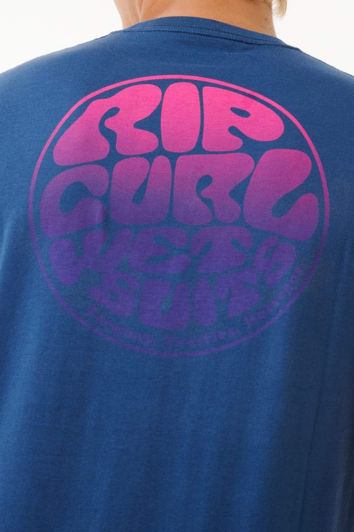 The Rip Curl Wetsuit Icon Tee features a crew neck, blue color, and a circular pink and purple "RIP CURL WETSUITS" bubble logo on the back, crafted from lightweight cotton.