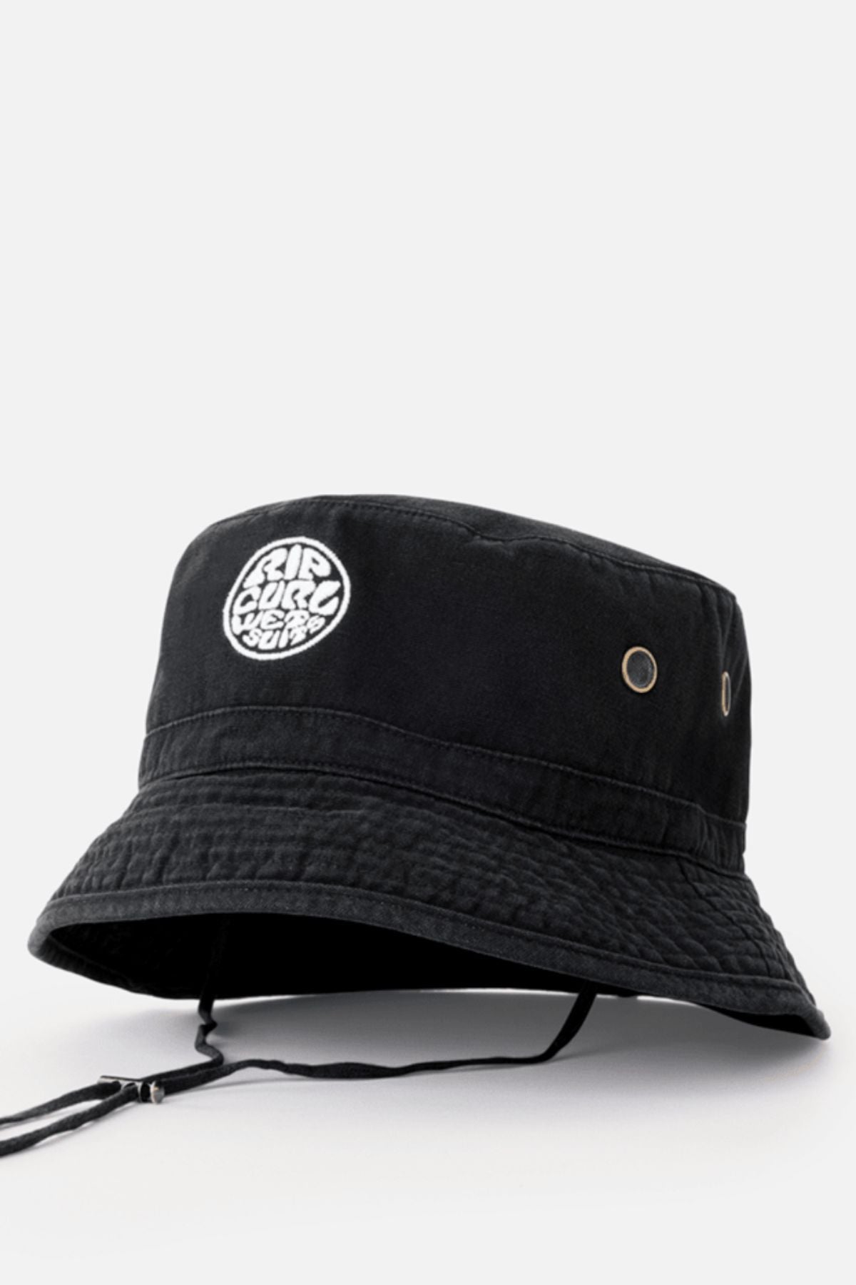 The Rip Curl Wetty Icon Bucket Hat is black with metal side eyelets, a chin strap, and a white embroidered circular logo on the front. Shown against a plain light gray background.