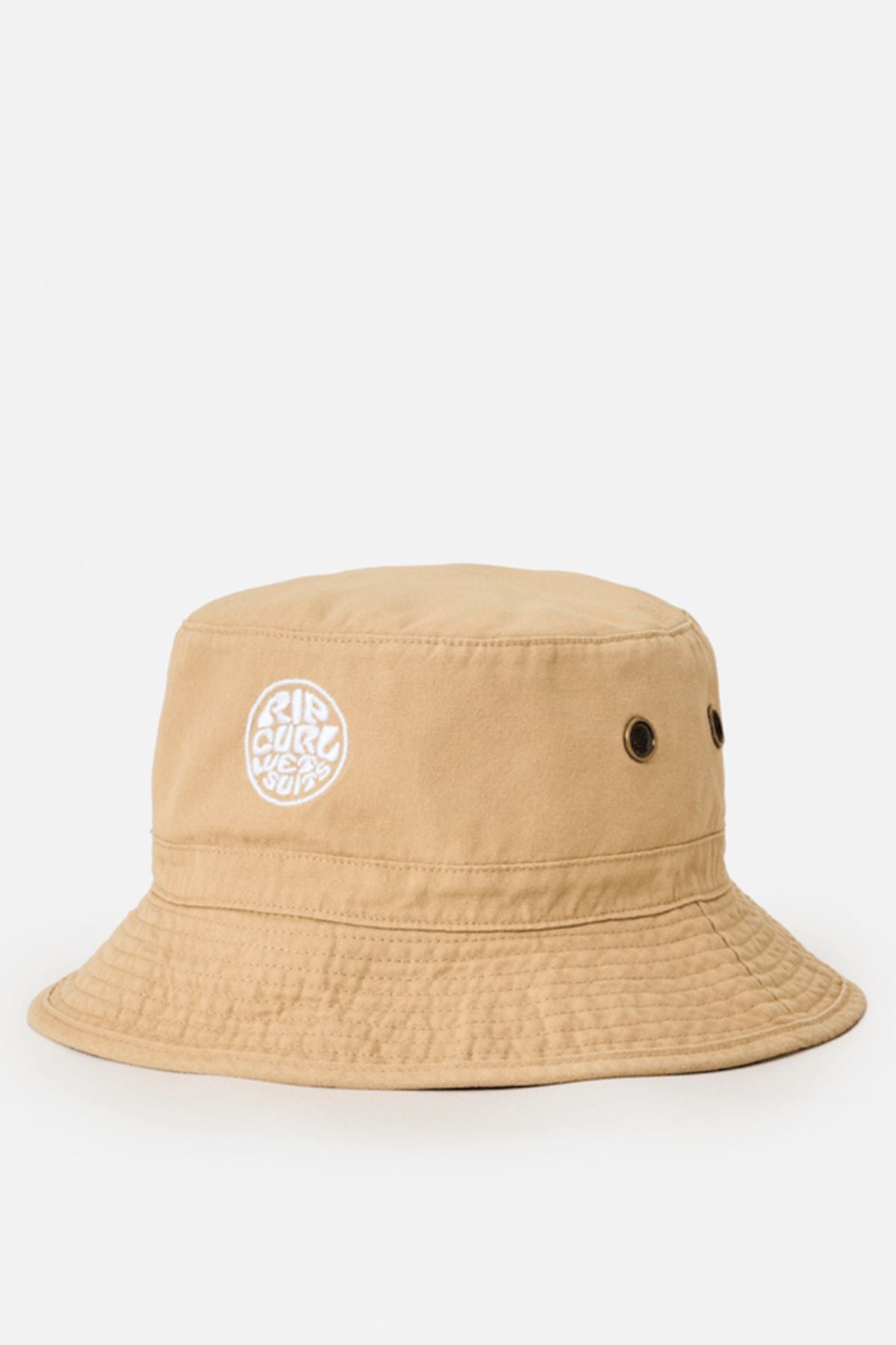 The Rip Curl Wetty Icon Bucket Hat is tan and made from organic canvas, with two metal eyelets per side and a white circular embroidered logo on the front. A downward-sloping brim and visible stitching add to its laid-back style.